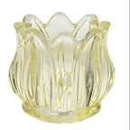 Three glass candle holders in pink, purple, and yellow on a white background