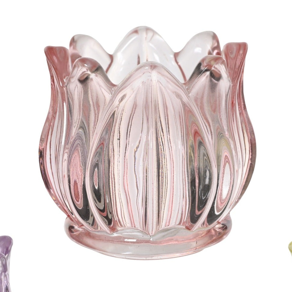 Three glass candle holders in pink, purple, and yellow on a white background