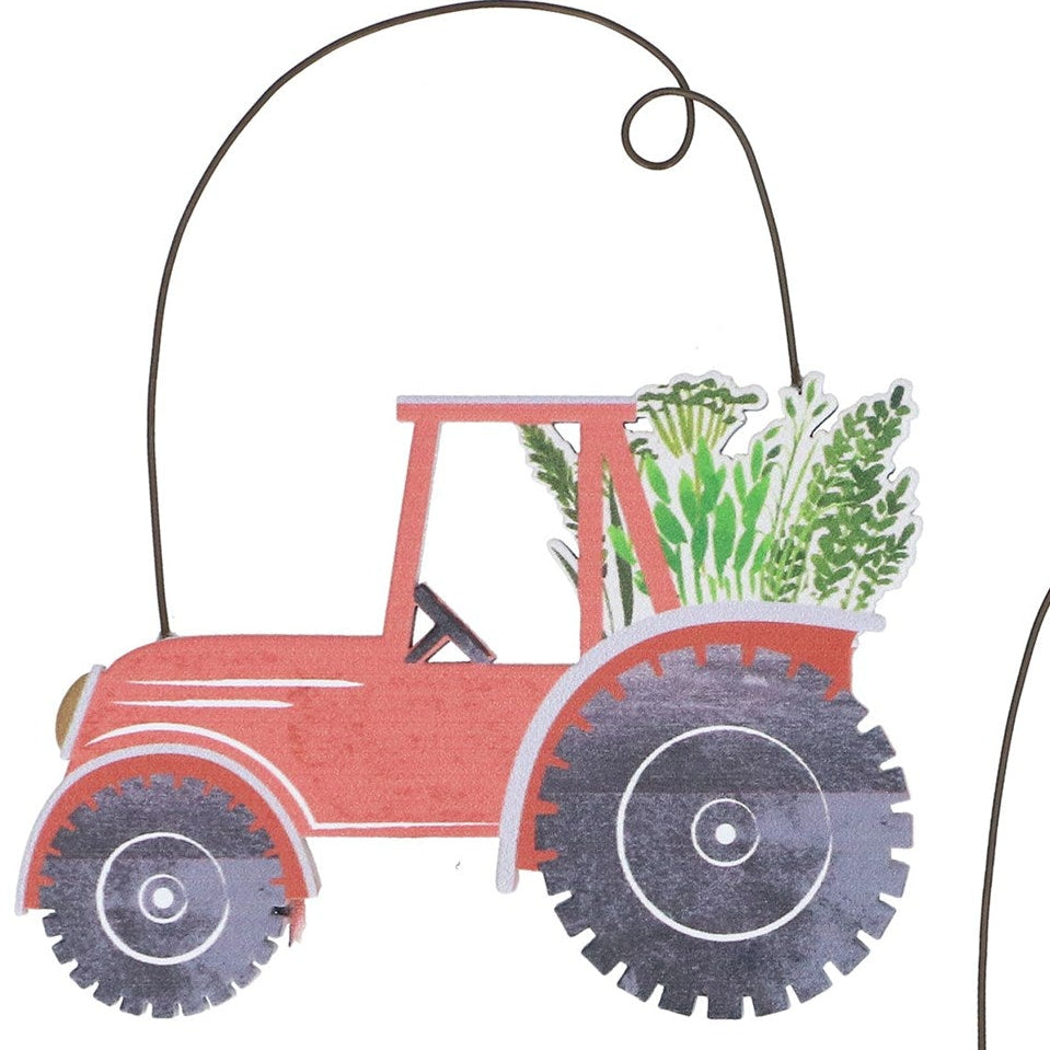 Two decorative metal tractors with plants on a white background