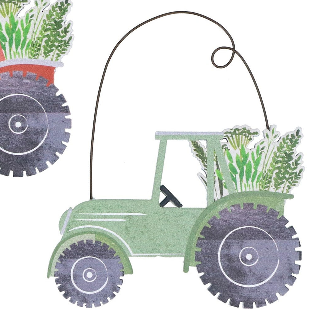 Two decorative metal tractors with plants on a white background