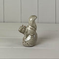 Beige mottled ceramic squirrel sitting on an acorn decoration