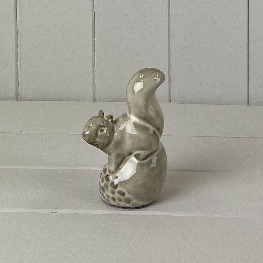 Beige mottled ceramic squirrel sitting on an acorn decoration