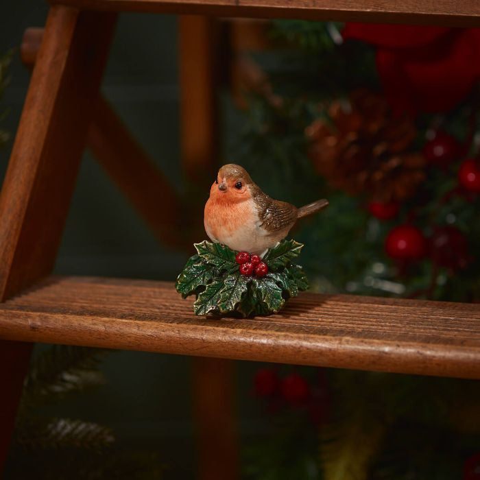 Festive robin sitting on holly ornament